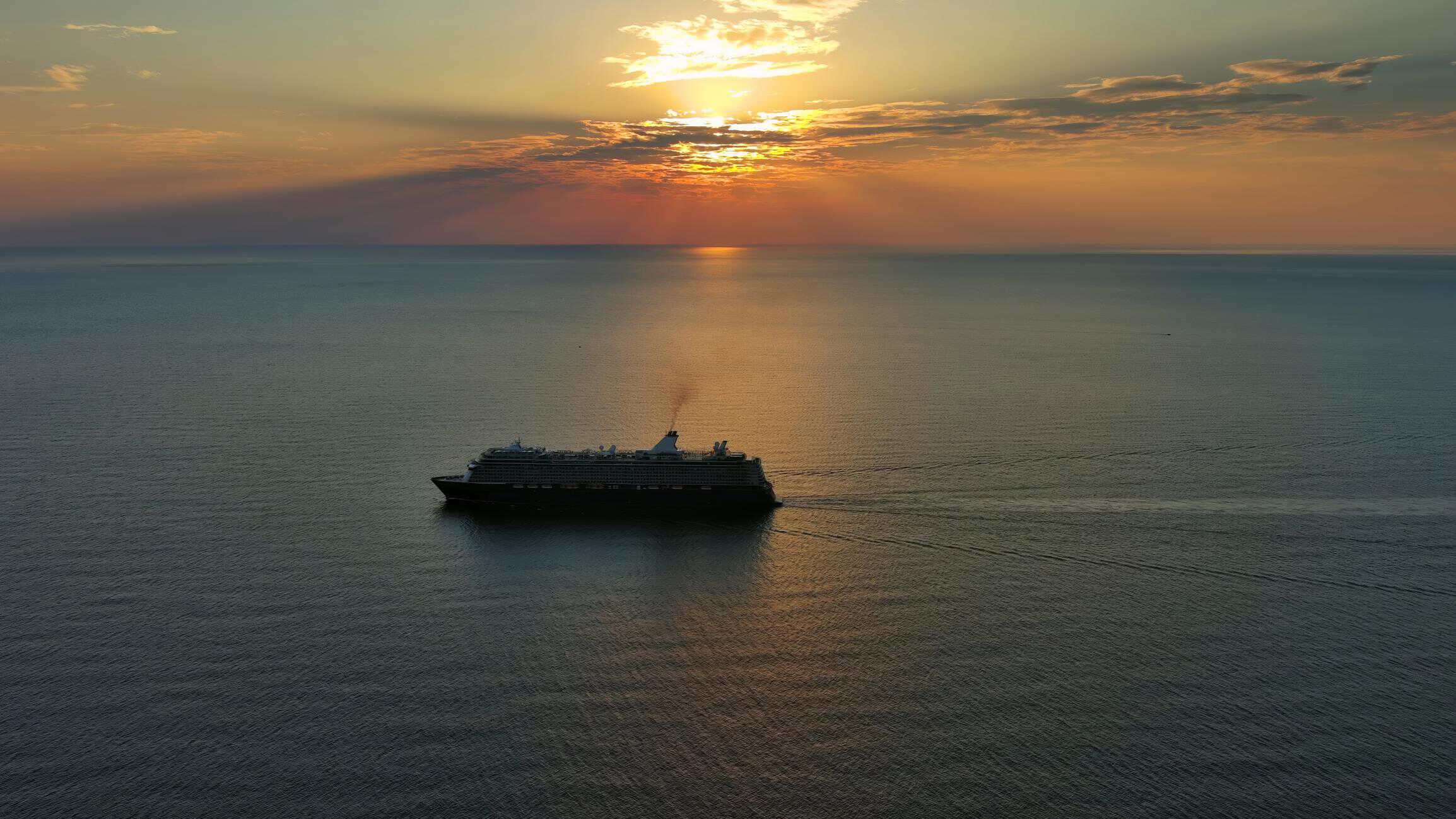 cruise ship sailing at sunset over the ocean representing the experience of a first cruise