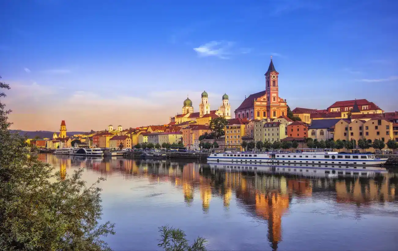 Luxury European river cruise sailing along the Danube River past the historic town of Passau at sunset