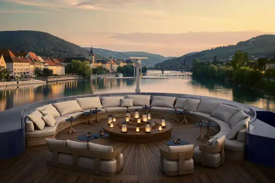 Luxury European river cruise sun deck at sunset with comfortable seating and scenic river views through a European town