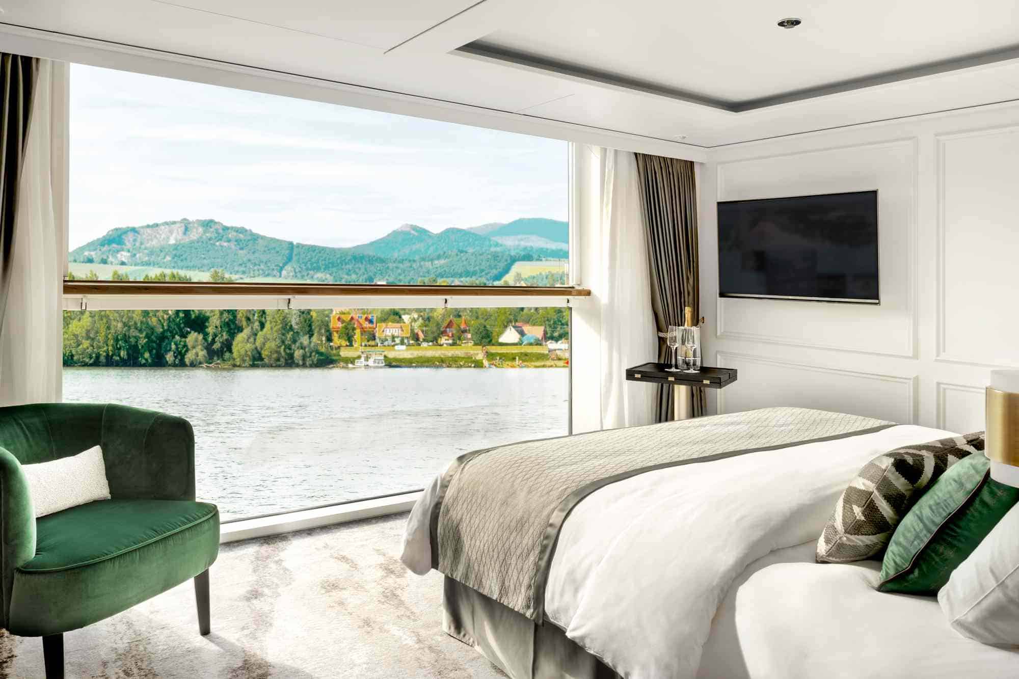 Luxury European river cruise suite with balcony view overlooking a scenic river and countryside