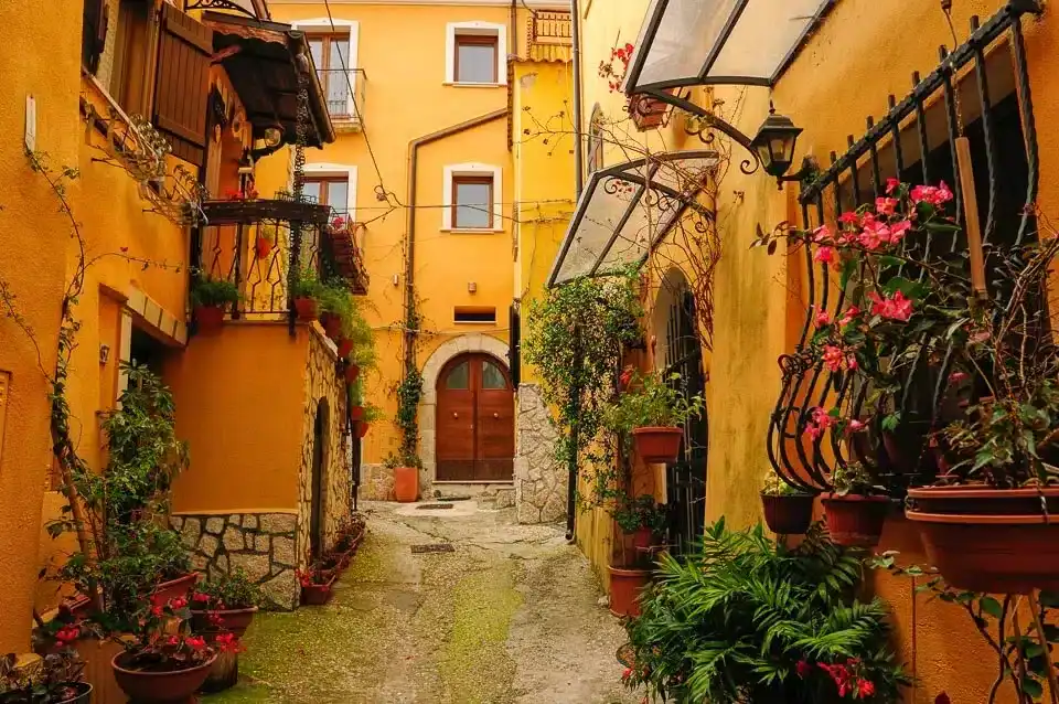 Best way to see Europe without rushing exploring a quiet Italian village street with colorful buildings and flowers