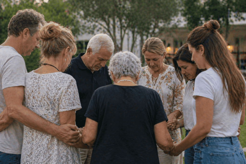 Church group standing in a circle praying together before a group trip