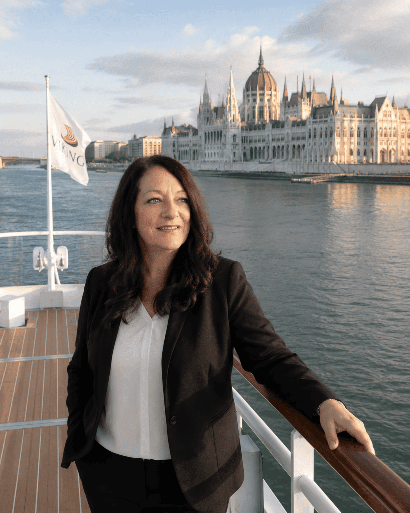 Solo female traveler standing on the bow of a river cruise ship sailing toward Budapest on the Danube River, 2026.