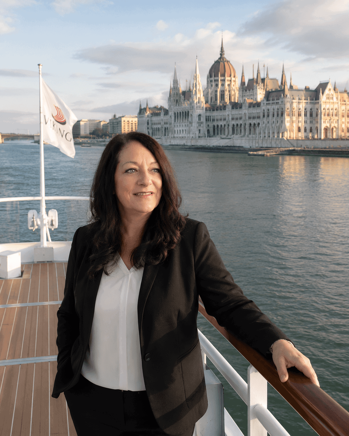 Solo female traveler standing on the bow of a river cruise ship sailing toward Budapest on the Danube River, 2026.