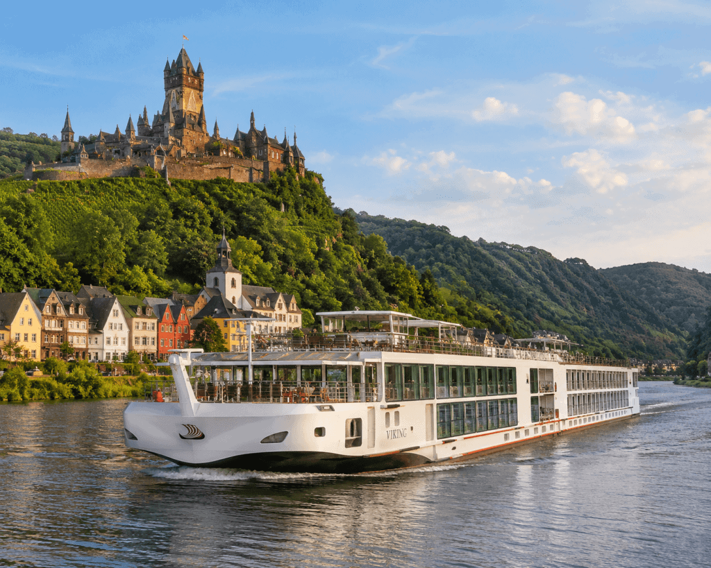 Viking river cruise longship sailing the Rhine River past a medieval castle on a clear day. 
