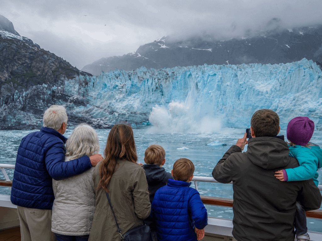 Family standing on Alaska cruise ship deck watching glacier calving, 2026