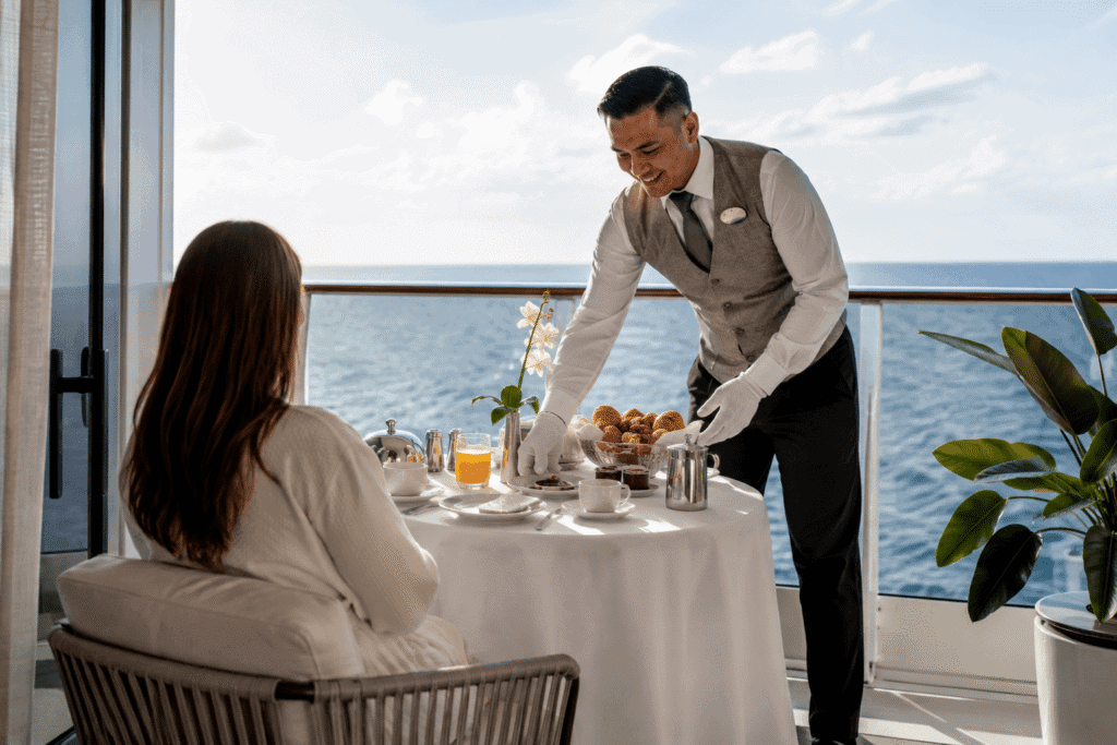 Haven butler serving breakfast with white tablecloth service on a Norwegian suite balcony