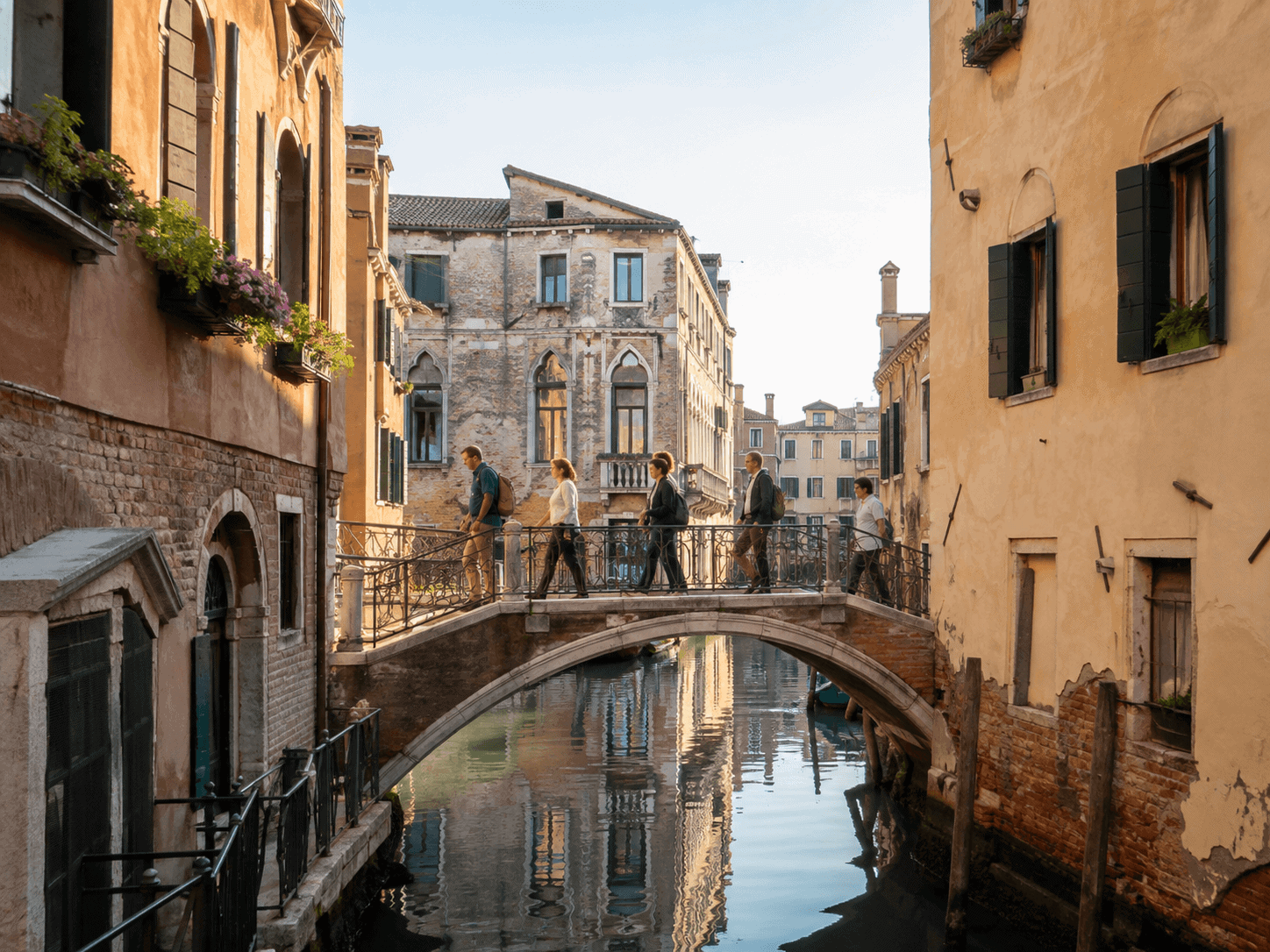 Small group of travelers crossing a quiet Venice canal bridge in early morning light
